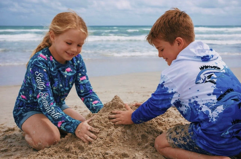 Two children building a sandcastle on a beach with ocean in the background